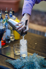 caucasian young cool red haired barista mixing a a cocktail in shaker with energy outdoors