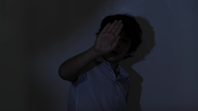 Kid showing stop gesture, a powerful statement on personal space. Relevant for educational material on respect and privacy. Suitable for awareness campaigns on anti-bullying and child autonomy.