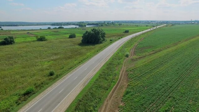 Country road along fields at summer sunny day. Aerial view