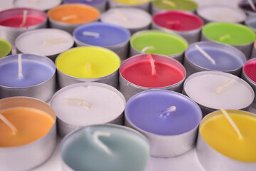 Many candles of different colors on a flat surface.
