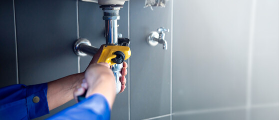Plumber fixing white sink pipe with adjustable wrench. - obrazy, fototapety, plakaty