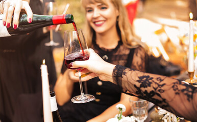 Crop women pouring wine during party