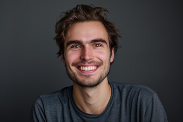 Obraz premium A man with a beard is smiling and wearing a grey shirt