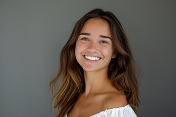 Naklejka premium A woman in a white off the shoulder top smiles for the camera