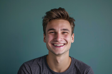 A young man in a grey shirt smiles for the camera