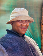 village smiling african social worker man with a hat standing in the yard