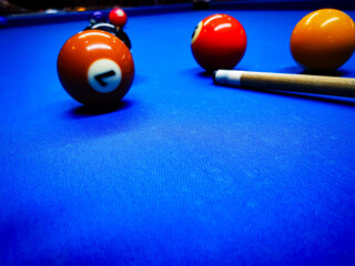 4 pool ball and a pool cue in focus on a blue pool table/ snooker table.