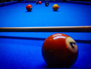 Colorful shot of 6 pool balls on a blue pool table / snooker table with a pool cue out of focus.