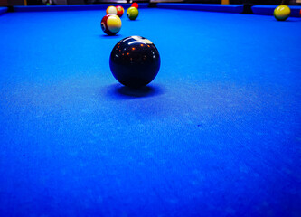 Cue ball in focus with other balls in background on pool table.