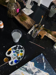 An art workshop with a palette of colorful paints, brushes in a glass