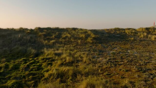 Drone footage of a grassy sand coastal dunes on the Laxe Beach at sunset in A Coruna, Galicia, Spain