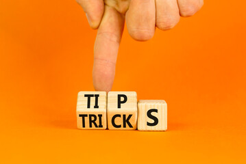 Tips and tricks symbol. Turned wooden cubes and changed the word tricks to tips. Beautiful orange table, orange background. Businessman hand. Business, tips and tricks concept. Copy space.