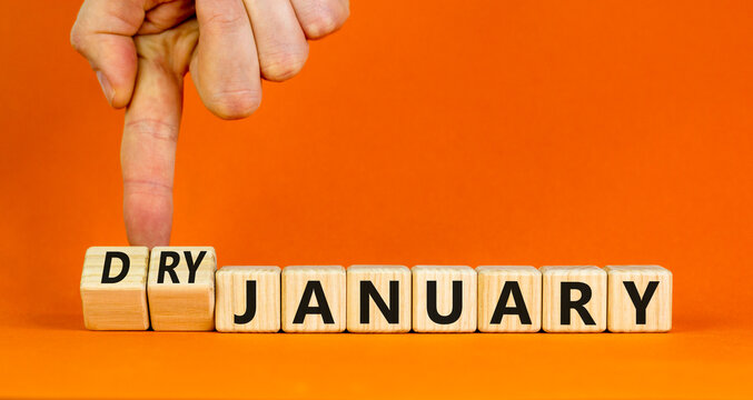 Dry January challenge symbol. Concept words Dry January on beautiful wooden cubes. Beautiful orange table orange background. Businessman hand. Dry January healthy lifestyle concept. Copy space.