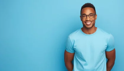 Foto op Canvas African american man waring blue t-shirt and glasses isolated on blue background © patternforstock