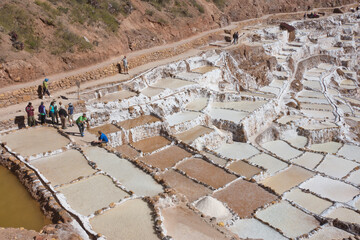 Obraz premium Maras, Peru – May 27 2018: Located in the Sacred Valley, Peru, the Maras Salt Mines or Salineras de Maras are ancient salt pans that have been in operation for more than 500 years. They are mined by l