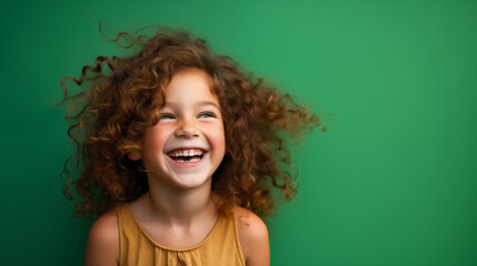 Portret studyjny dziewczynki uśmiechniętej na zielonym tle z dużą ilością wolnego tła - obrazy, fototapety, plakaty