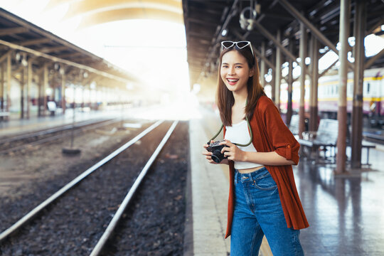 Happy young Asian woman traveler smiling and holding camera with looking for tourist attractions.