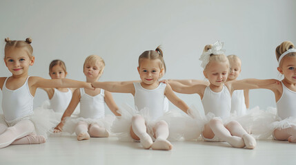 Little ballerinas girls and boys doing splits on the white floor, copy space. Smiling babies...