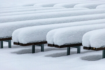 wooden benches covered with a thick blanket of snow, play of light and shadows, rhythm