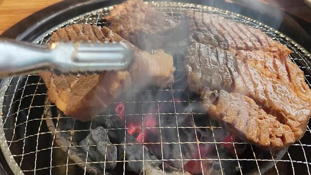 한국 전통 음식 돼지 갈비를 집게로 뒤집어 가면서 숯불에 굽는 