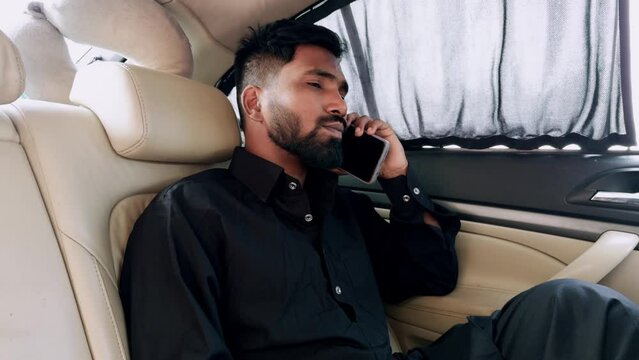 Businessman talking on phone while sitting in luxury car interior