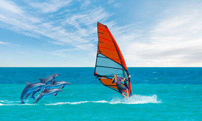 Dolphin jumping on the water - Beautiful cloudy sky with Windsurfer Surfing The Wind On Waves In Alacati - Cesme, Turkey