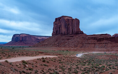 Desert landscape with red rocks and dry vegetation on red sands in Monument Valley, Navajo Nation,  Arizona - Utah