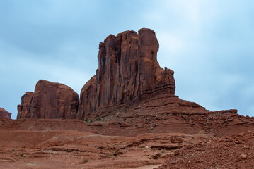 Fototapeta premium Desert landscape with red rocks and dry vegetation on red sands in Monument Valley, Navajo Nation, Arizona - Utah