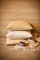 Fototapeta na wymiar Comfortable cushions and white mug of hot drink in cozy living room