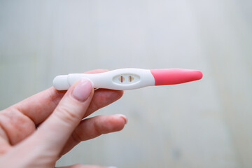 Woman hand holding positive pregnancy test with two lines on it. Pregnancy or fertility concept. High quality photo.