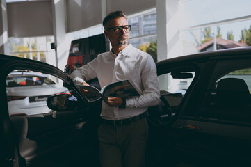 Adult man customer male buyer client wearing shirt read catalog papers documents look aside choose...