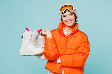 Skater smiling young woman wearing warm padded windbreaker jacket hat ski goggles mask hold in hand...