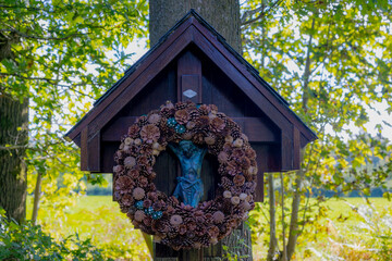 Jesus cross sign hanging on the tree with Autumn pine cone seed wreath around, The Christian cross...