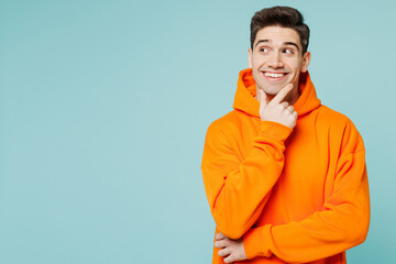 Young man he wears orange hoody casual clothes put hand prop up on chin, lost in thought and...
