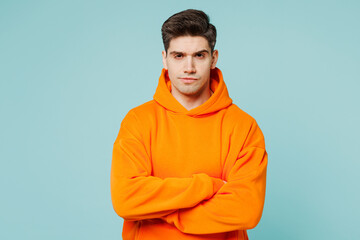 Young frowning upset grumpy man he wears orange hoody casual clothes hold hands crossed folded look...