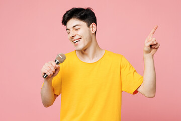 Young man he wears yellow t-shirt casual clothes sing song in microphone at karaoke club point...