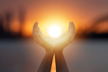 Hands holding the sun at dawn or sunset twilight. Hope Freedom and spirituality concept