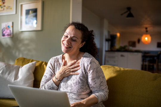 Happy smiling woman having video call on laptop at home