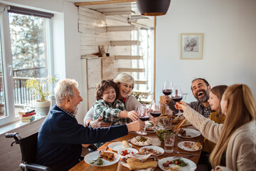 Multi-generational family enjoying meal and toasting with wine at home