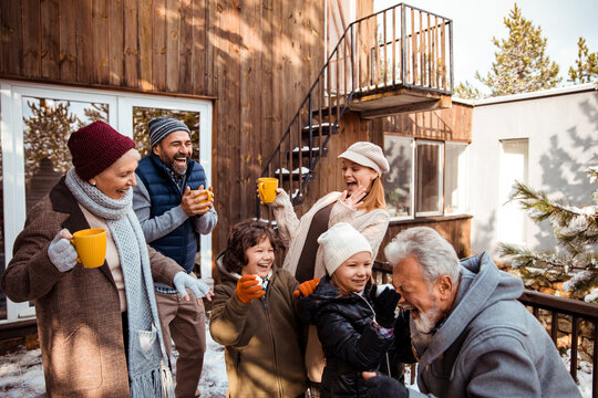 Happy family laughing and drinking warm beverages outdoors in winter