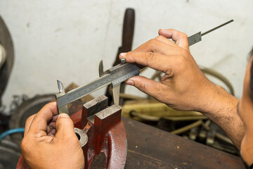 Close up scene the machine operator measuring dimension of cast iron parts by Vernier caliper.