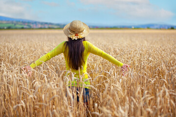young girl in a hat in a wheat field - 714840903