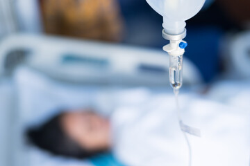 Close up set iv fluid intravenous drop saline drip in hospital room with blurry patient woman and...