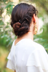 Back view of unrecognizable young woman with brunette hair in white wedding dress and vintage gold jewelry earrings