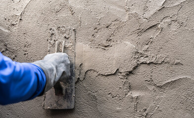 Hand plasterer plastering cement wall background, hand worker brush rough concrete floor for smooth...