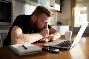Man working on laptop at home with coffee and notebook - obrazy, fototapety, plakaty