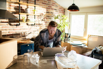 Young man using smartphone on move day in kitchen