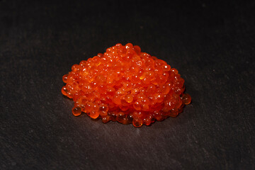 Red trout caviar on a black background.