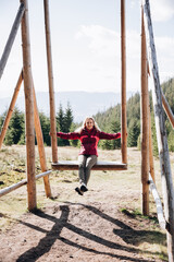 woman traveling in the mountains. a woman sits on a large wooden swing high in the mountains. autumn in the mountains