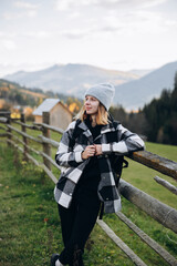 Fototapeta na wymiar a beautiful girl in a checkered shirt travels in the mountains. overcome the route in the mountains with a backpack. autumn landscapes. Carpathians